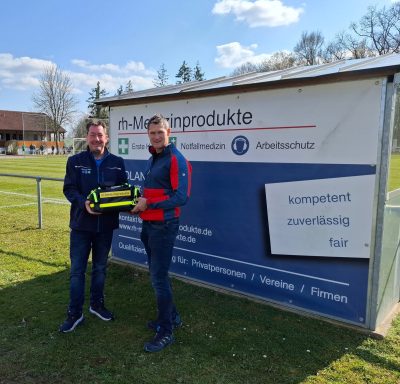 Zwei Männer stehen vor einem Schild mit Informationen zu Sportprodukten.